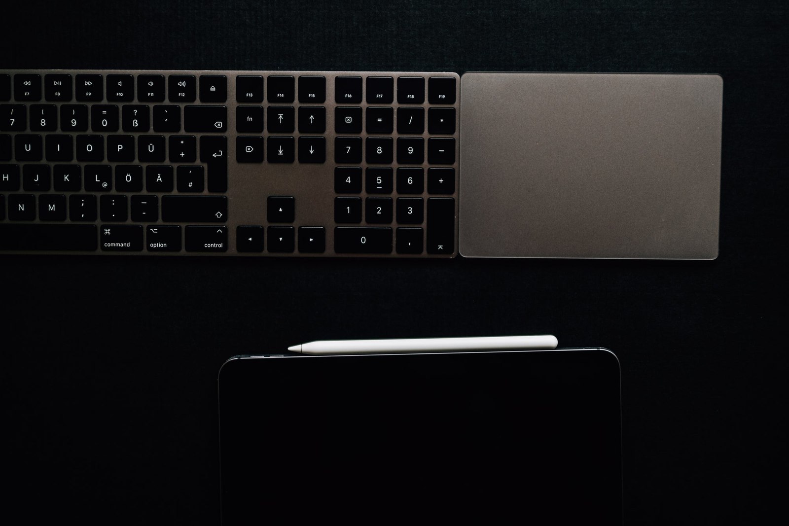 A Keyboard And Tablet On A Black Surface