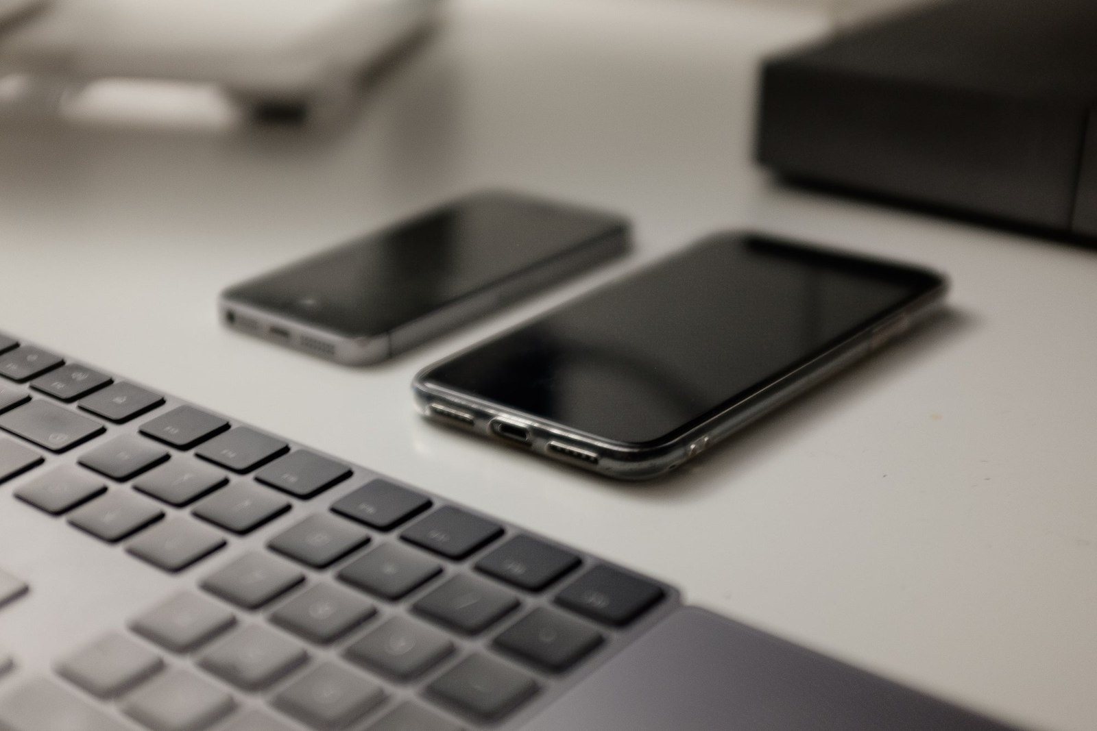 A White Table With Two Cell Phones And A Keyboard